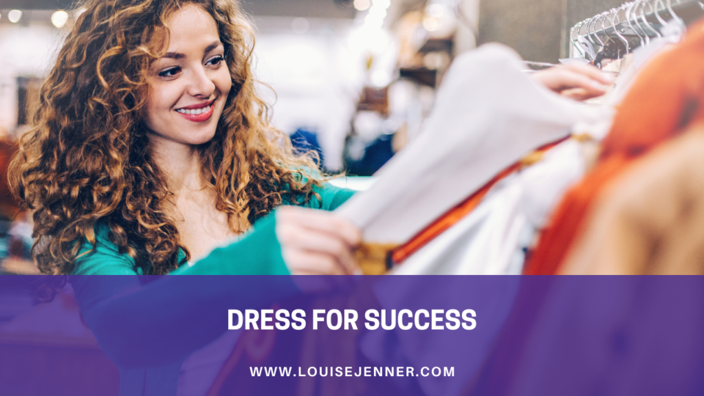 A woman smiling as she selects clothes from a rail in order to dress for success in her new job.