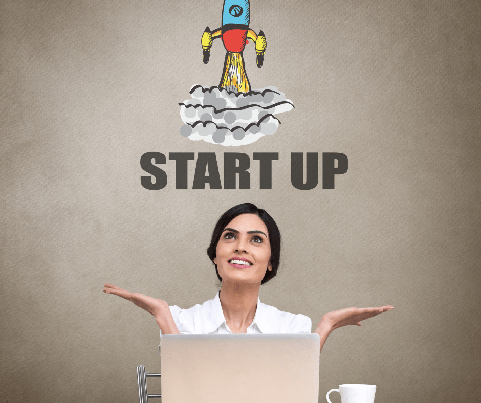 Woman behind a laptop with her hands facing upwards in an open gesture. She's smiling and looking up. Above her head are the words START UP and above that is a cartoon image of a rocket taking off.