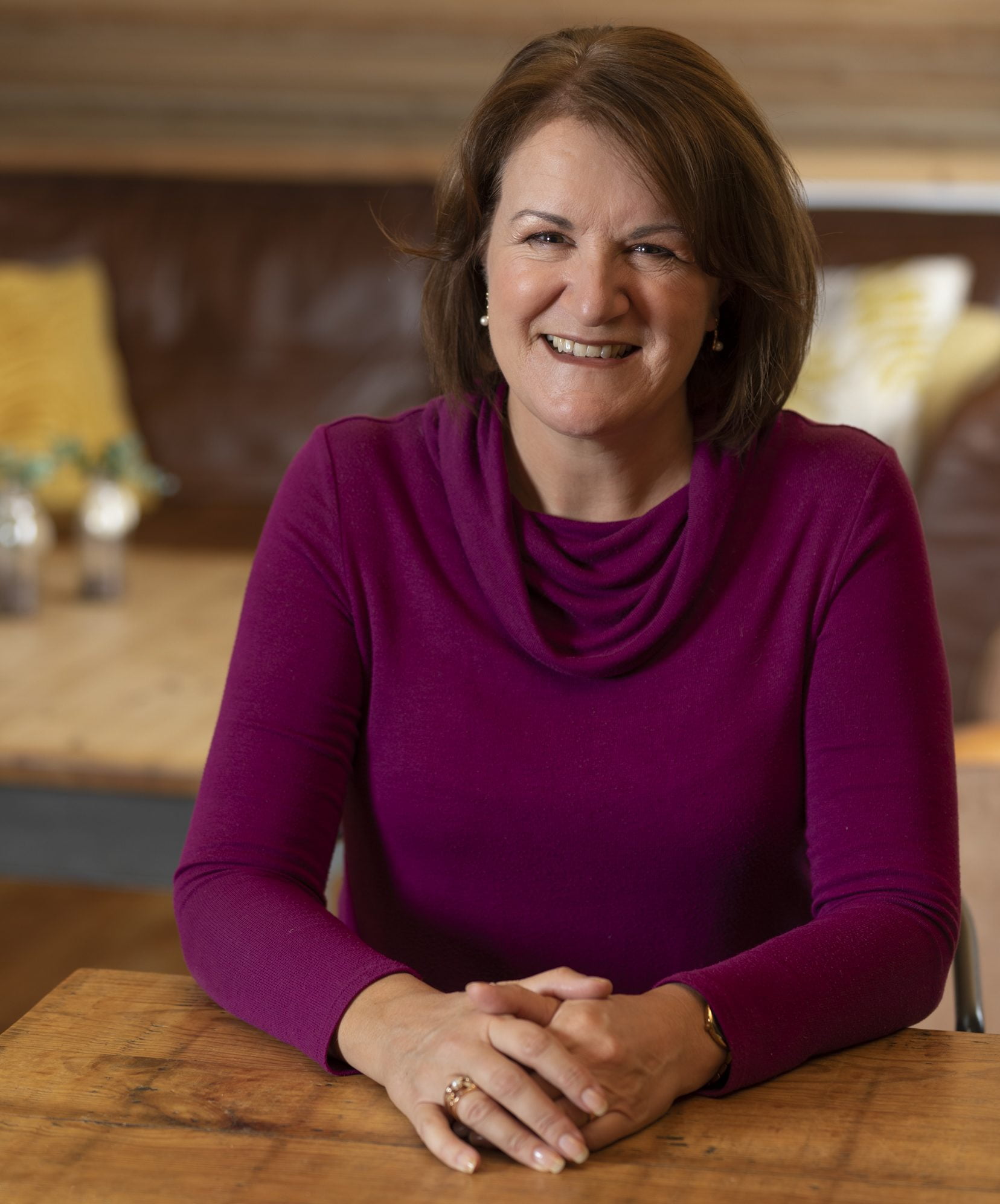 Louise Jenner, The Dream Job Coach sitting at a wooden table, wearing a purple top waiting to greet a career coaching client.