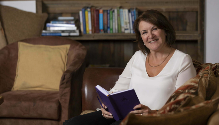 Louise Jenner sitting on a sofa holding a book