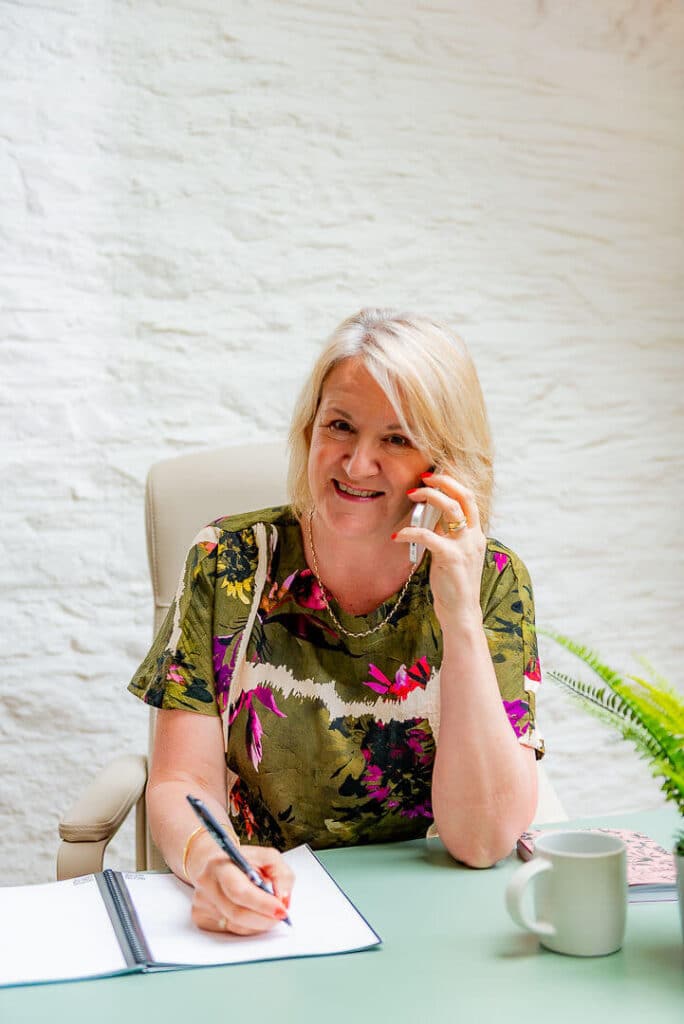 Louise Jenner is on the phone to a career coaching client. She's smiling and taking notes.