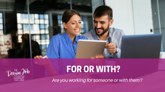 Brown-haired female in a blue blouse sits alongside a brown-haired male with a beard. They are working with each other at a desk. There's an open laptop and they're looking at a notebook and smiling. Louise Jenner The Dream Job Coach would say they are working with each other.